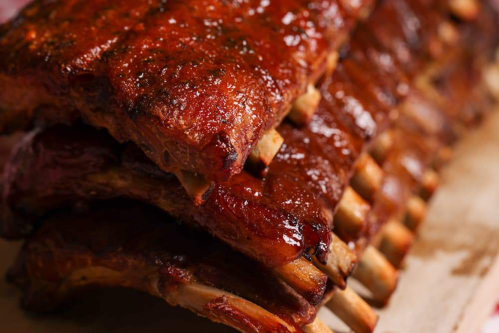 Stack of slow-cooked Texas style pork ribs glazed with a thick, glossy barbecue sauce.